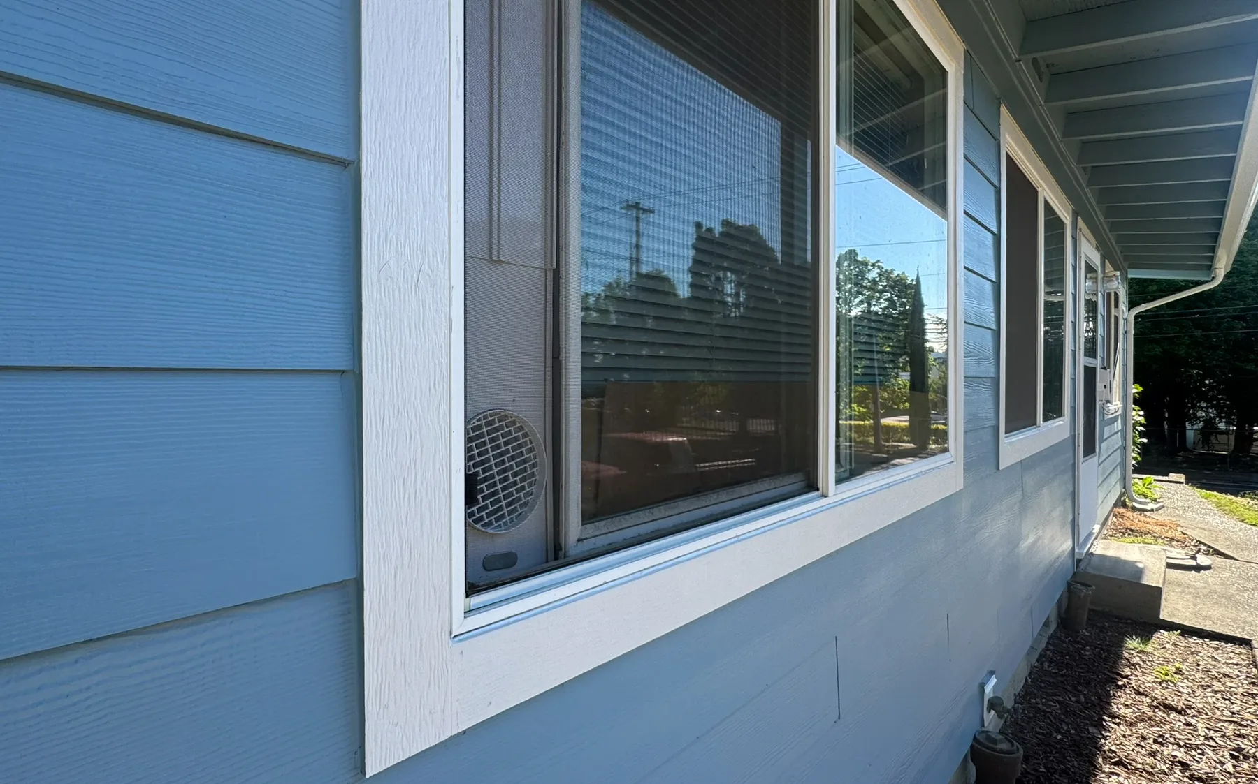 Fresh blue exterior paint and white trim around Portland home windows